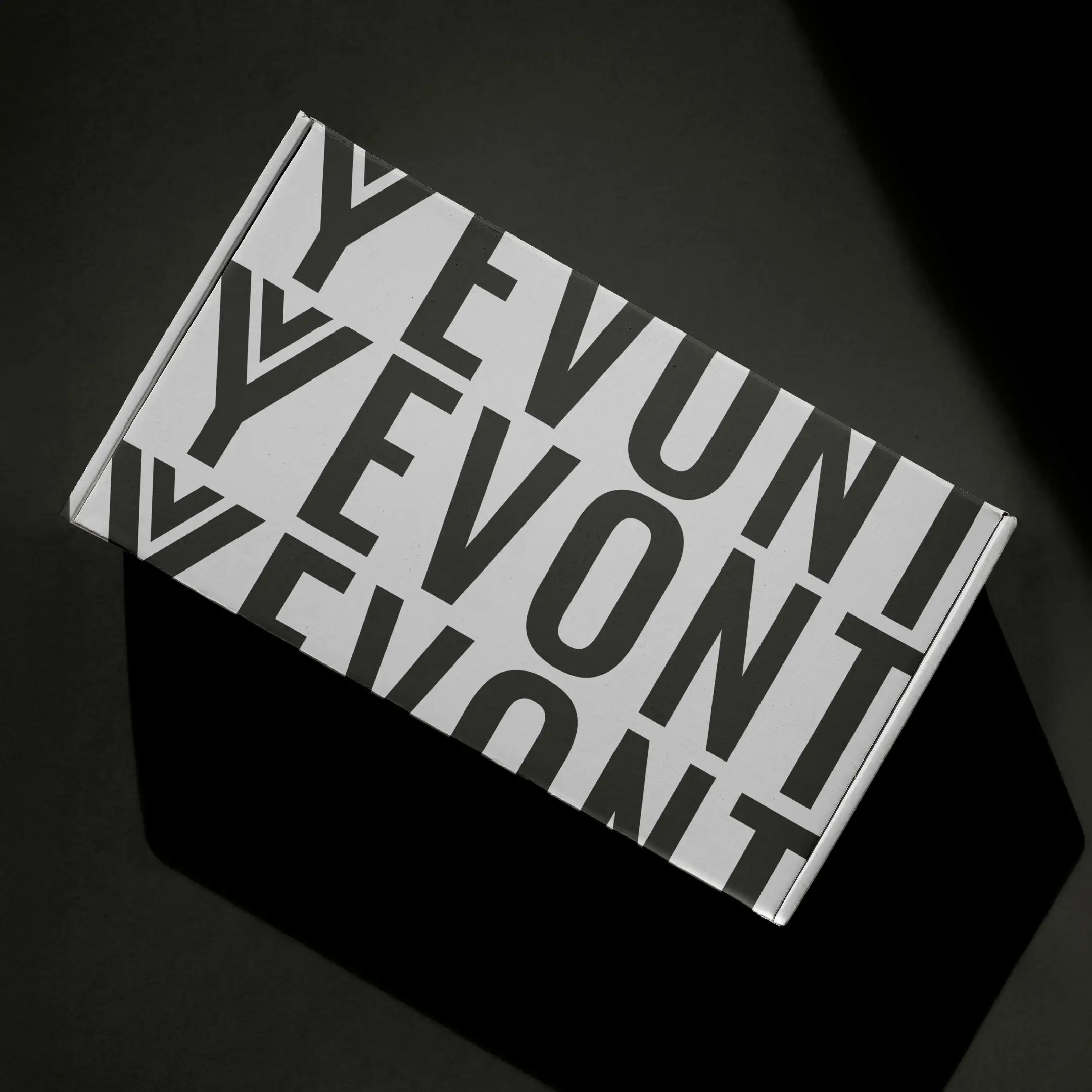 Yevont printed packaging photographed in hard light on a dark ground