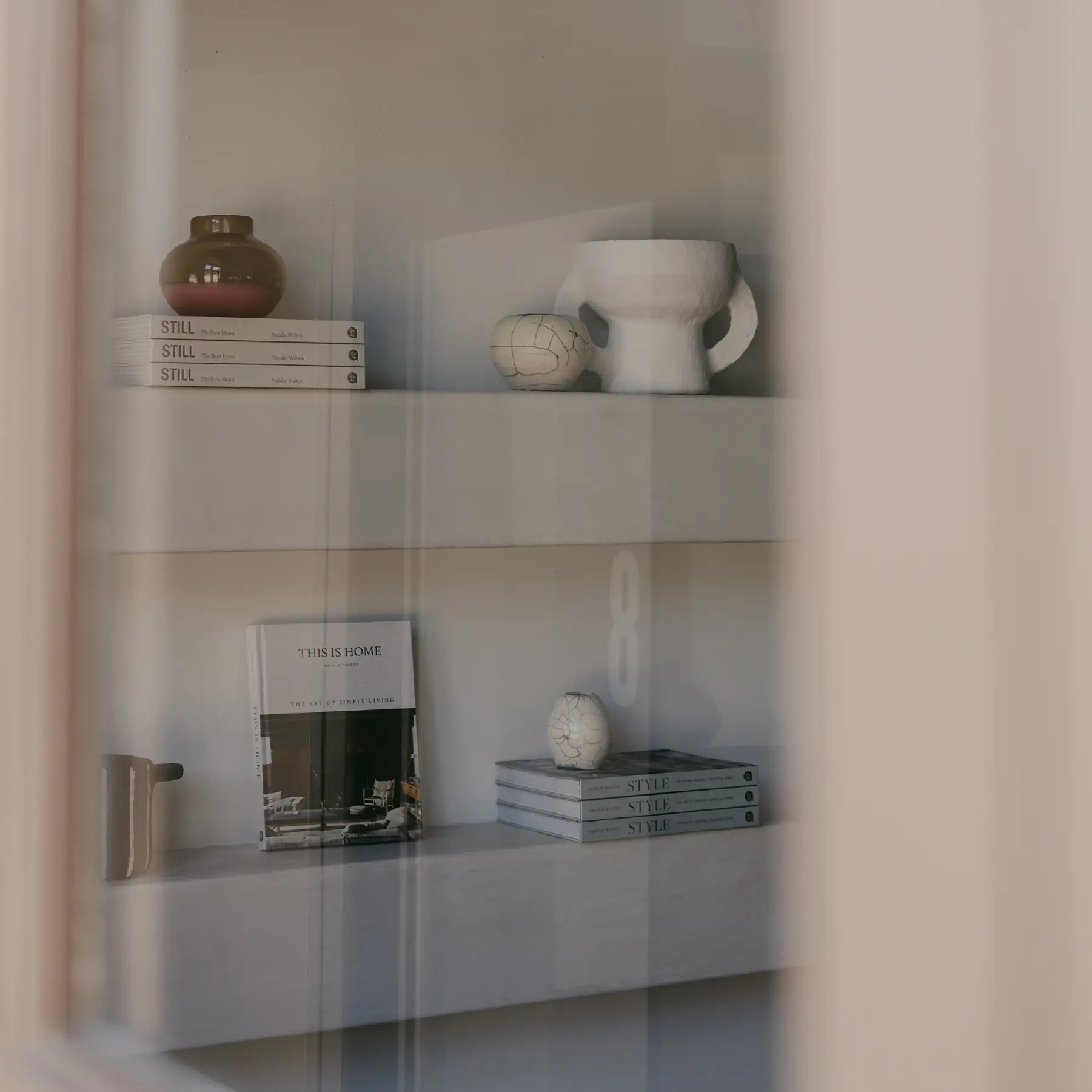 Ochre and Silk styling detail — ceramics and books on a shelf seen through fluted glass
