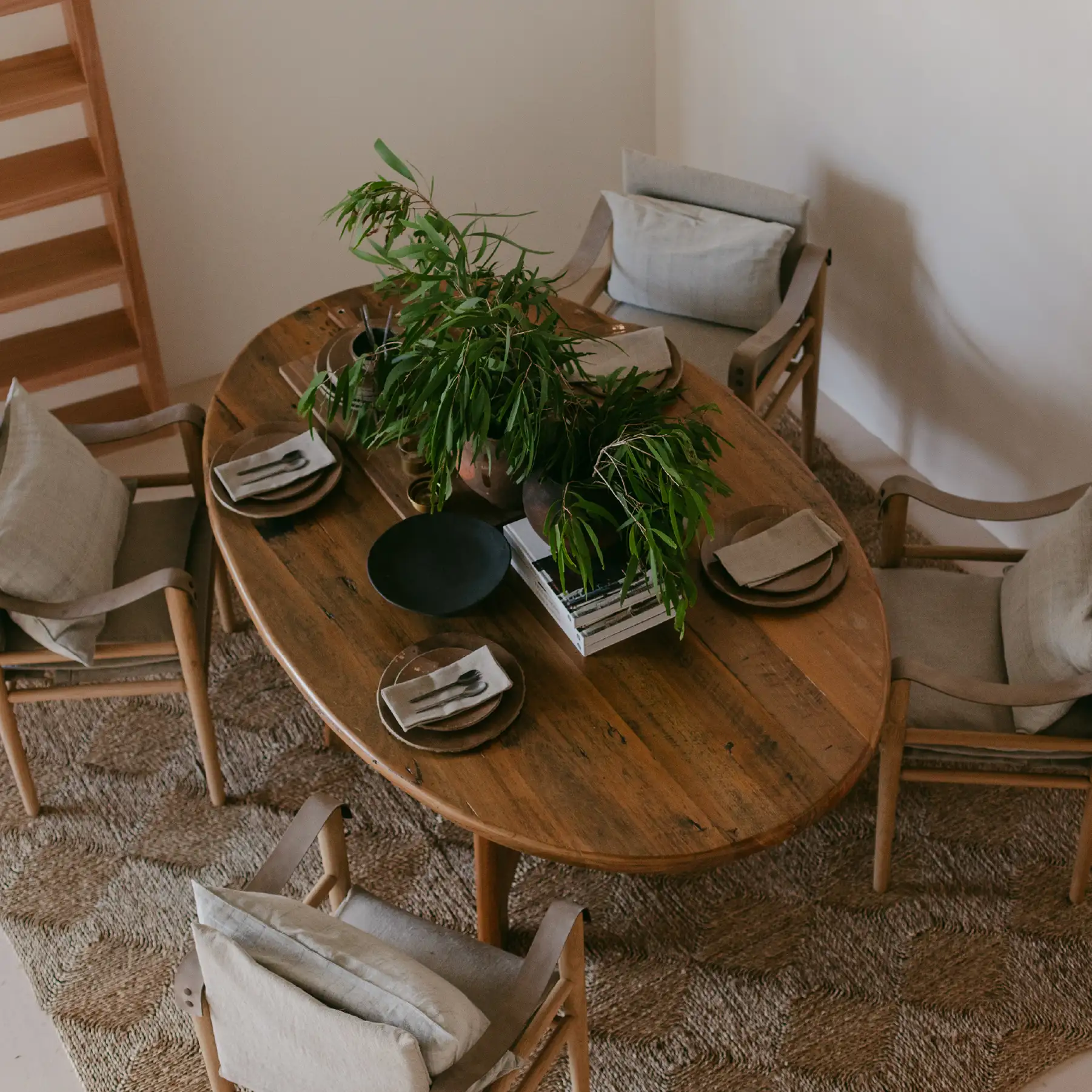 Ochre and Silk interiors photography — a round timber dining table with linen chairs and a trailing plant