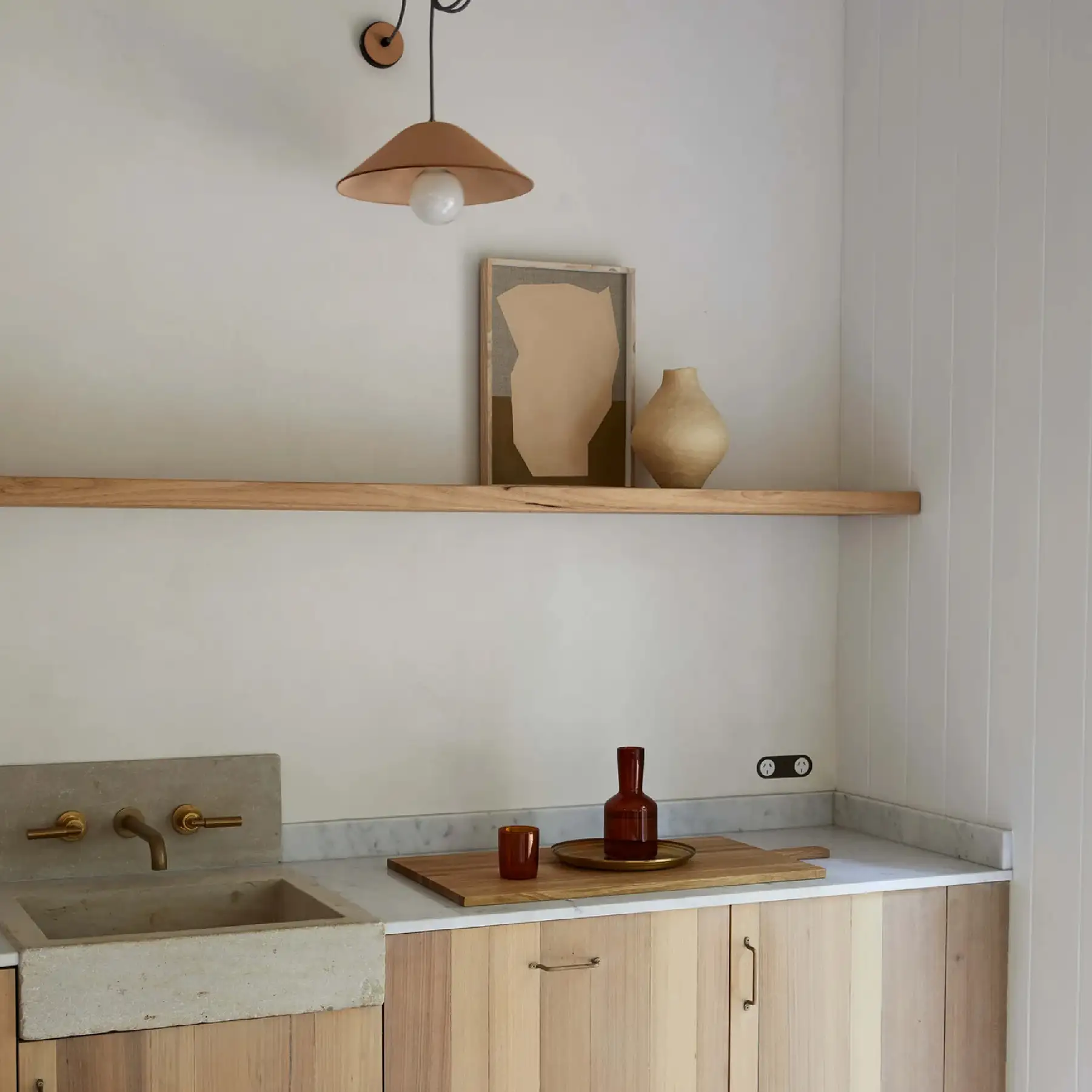 Ochre and Silk interiors photography — pale timber kitchenette with a concrete sink and terracotta pendant