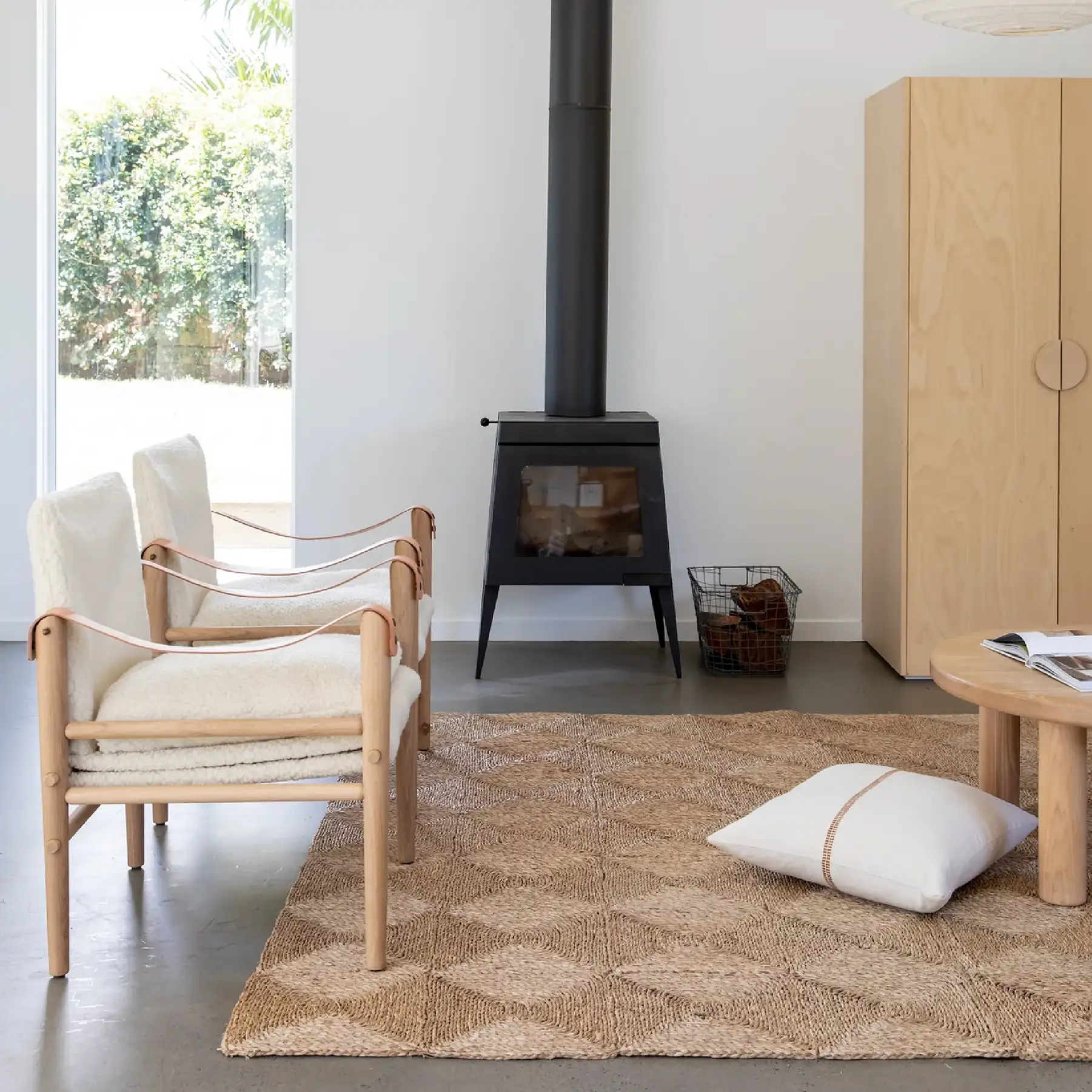 Ochre and Silk interiors photography — pale living room with a wood heater, safari chairs and a jute rug