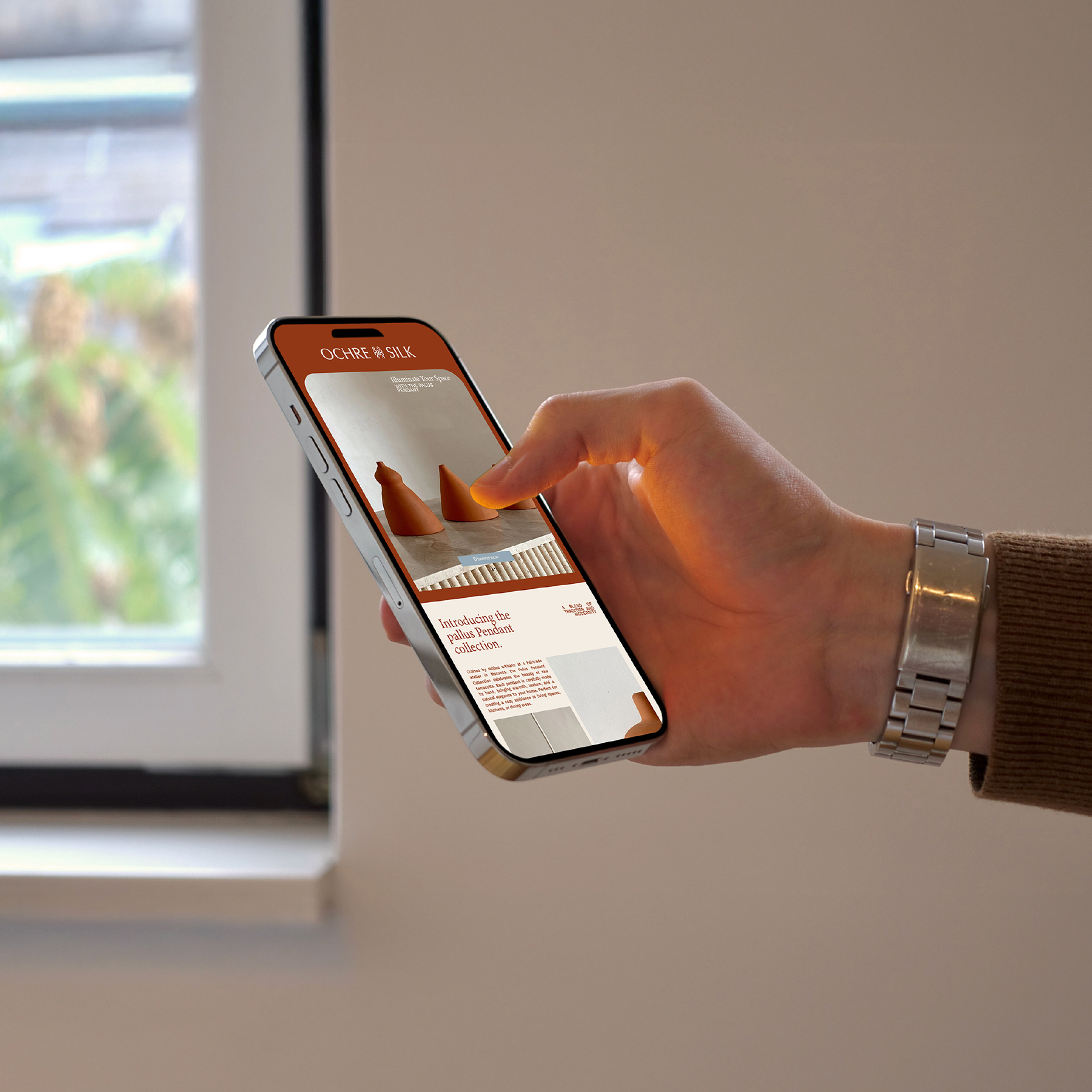 Ochre and Silk website open on a phone held in front of a window