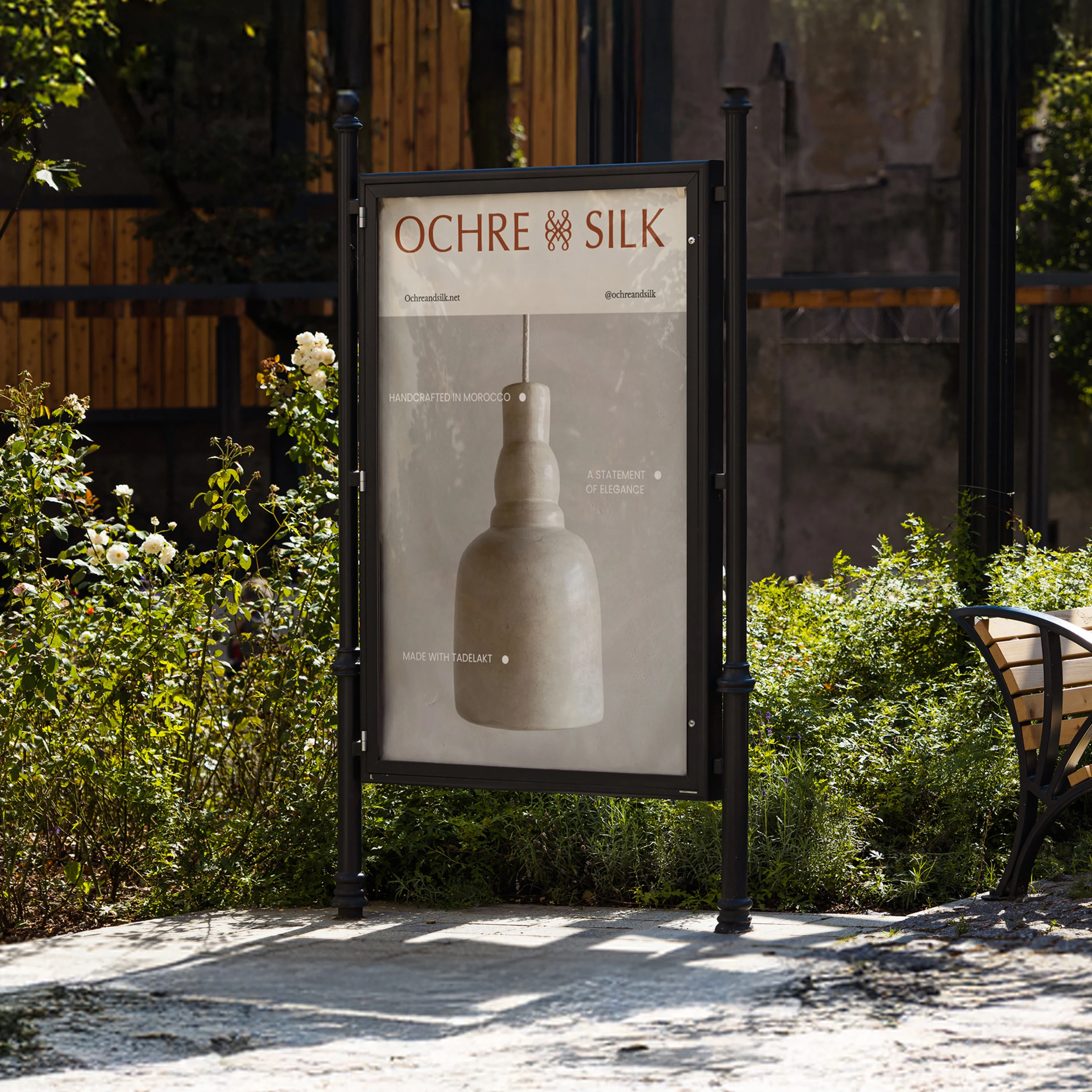 Ochre and Silk poster in a street-side frame, set among greenery