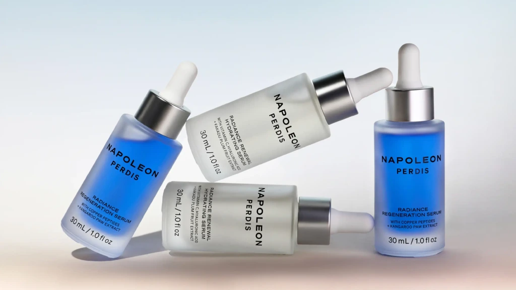 Four Napoleon Perdis serum bottles arranged on a soft blue gradient