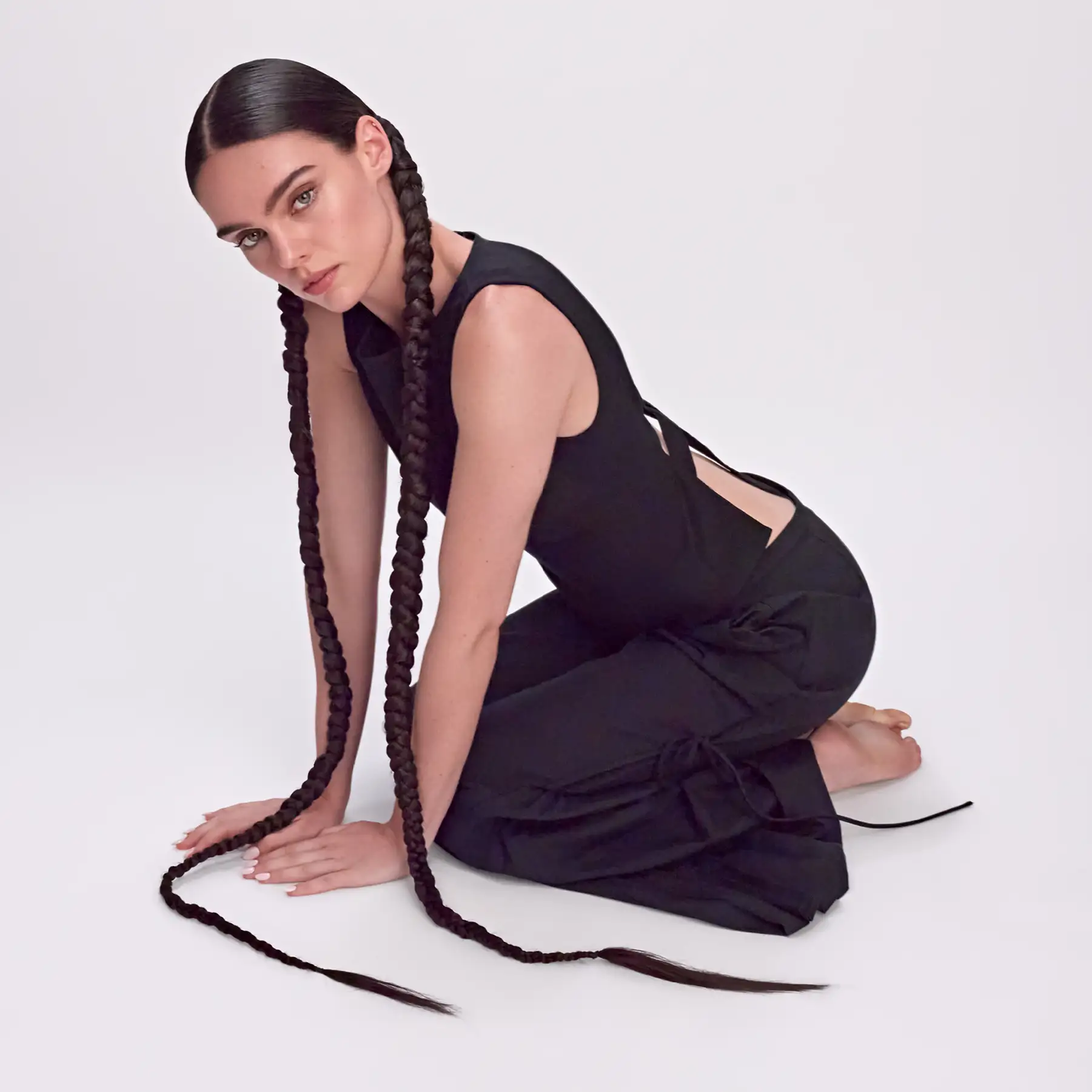 CPR Hair editorial photography — model kneeling with two braids trailing across the floor