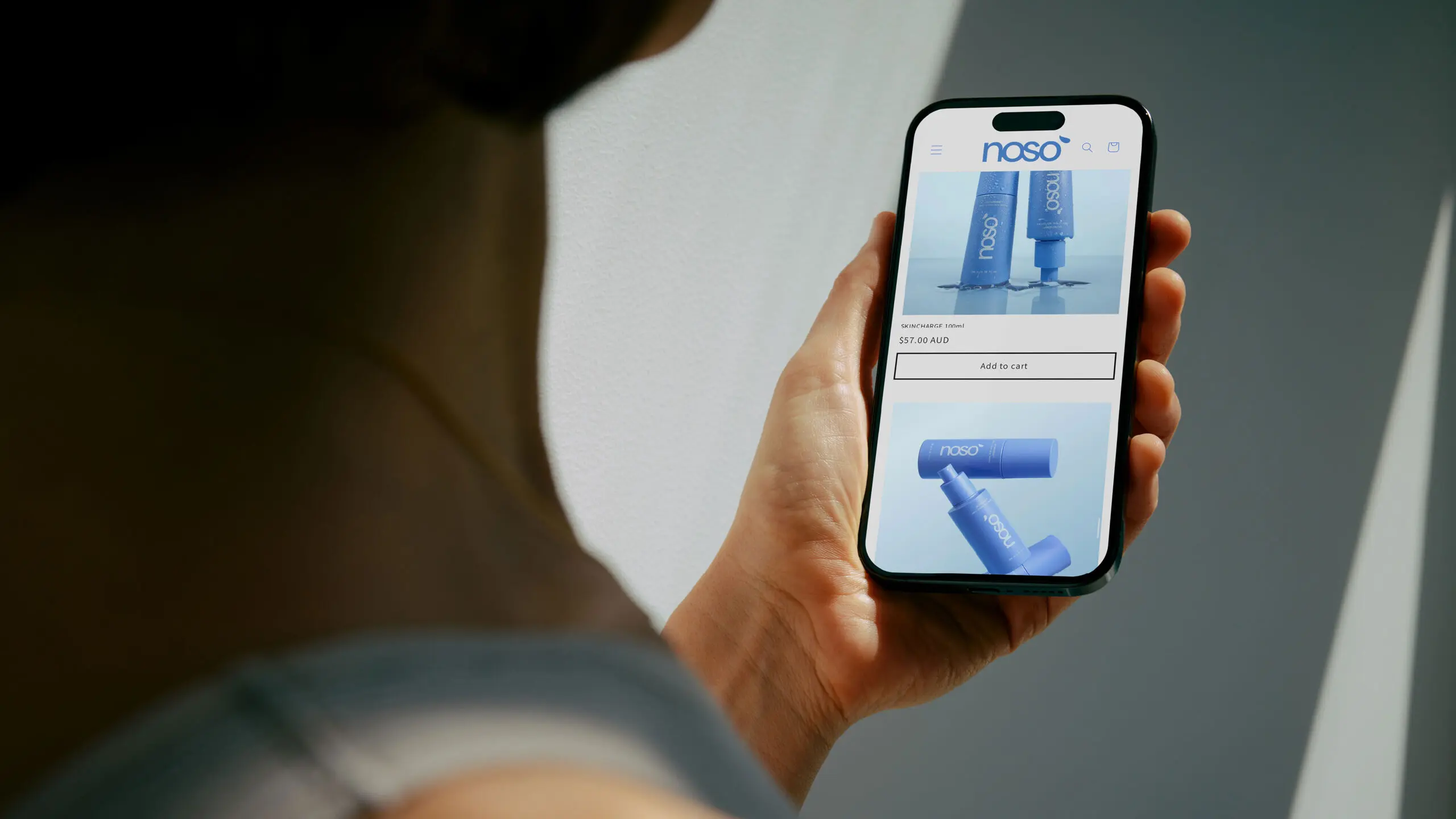 Noso e-commerce site shown on a phone held by an athlete